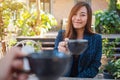 A beautiful asian woman clinking coffee mugs with friend in cafe Royalty Free Stock Photo
