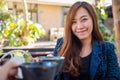 A beautiful asian woman clinking coffee mugs with friend in cafe