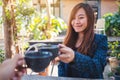 A beautiful asian woman clinking coffee mugs with friend in cafe Royalty Free Stock Photo