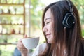 A beautiful Asian woman close her eyes and listening to music with headphone while drinking coffee with feeling happy and relax in Royalty Free Stock Photo