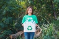 A woman collecting garbage and holding a recycle bin with plastic bottles in the outdoors