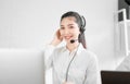 Beautiful Asian woman consultant wearing microphone headset of customer support phone operator at workplace.