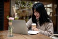 A beautiful Asian woman is working remotely at a cafe in the city, working on her laptop Royalty Free Stock Photo