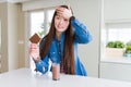 Beautiful Asian woman drinking chocolate milkshake and holding chocolate bar stressed with hand on head, shocked with shame and Royalty Free Stock Photo