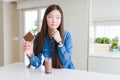 Beautiful Asian woman drinking chocolate milkshake and holding chocolate bar serious face thinking about question, very confused Royalty Free Stock Photo