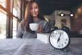 A beautiful Asian woman drinking coffee in the morning with black alarm clock Royalty Free Stock Photo