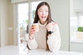 Beautiful Asian woman drinking a coffee in a take away paper cup pointing and showing with thumb up to the side with happy face Royalty Free Stock Photo