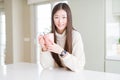 Beautiful Asian woman drinking a cup of coffee with a happy face standing and smiling with a confident smile showing teeth Royalty Free Stock Photo