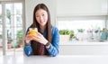 Beautiful Asian woman drinking a glass of fresh orange juice with a happy face standing and smiling with a confident smile showing Royalty Free Stock Photo