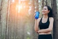 Beautiful asian woman drinking protein shake in the forest