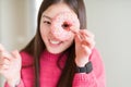 Beautiful Asian woman eating pink sugar donut very happy pointing with hand and finger to the side Royalty Free Stock Photo