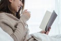 Beautiful asian woman enjoying warm coffee and reading book. Royalty Free Stock Photo