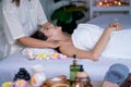 Beautiful Asian woman feel relax and relieve during lie on bed and get spa massage with several accessories in front of bed Royalty Free Stock Photo