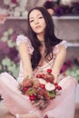 Beautiful asian woman florist in pink dress with bouquet of flowers in hands in flower store Royalty Free Stock Photo