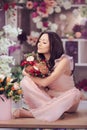 Beautiful asian woman florist in pink dress with bouquet of flowers in hands in flower store Royalty Free Stock Photo