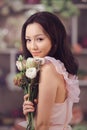 Beautiful asian woman florist in pink dress with bouquet of flowers in hands in flower store Royalty Free Stock Photo