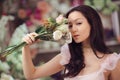 Beautiful asian woman florist in pink dress with bouquet of flowers in hands in flower store Royalty Free Stock Photo