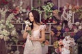Beautiful asian woman florist in pink dress with bouquet of flowers in hands in flower store Royalty Free Stock Photo