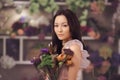 Beautiful asian woman florist in pink dress with bouquet of flowers in hands in flower store Royalty Free Stock Photo