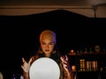 Beautiful Asian woman fortune teller using crystal ball on red table to forecast future