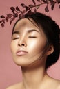 Beautiful asian woman with fresh daily makeup. Vietnamese beauty girl in spa treatment with green leafs near face Royalty Free Stock Photo