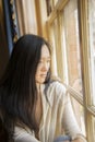 Beautiful Asian Woman gazes out a City Window