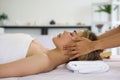 Beautiful asian woman getting face massage in beauty spa. Young woman with closed eyes relaxing in indoor spa while getting head Royalty Free Stock Photo