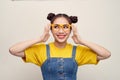 Beautiful Asian woman has two buns of hair wearing a jeans dungaree and adjusting glasses