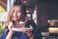 Asian woman holding chocolate cake roll and whipped cream and fork with feeling happy and enjoy eating in the modern loft cafe Royalty Free Stock Photo