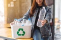 A beautiful woman holding and collecting recyclable garbage plastic bottles into a trash bin at home Royalty Free Stock Photo