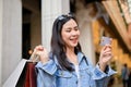 Beautiful Asian woman holding credit card and carrying shopping bags while shopping at city mall Royalty Free Stock Photo