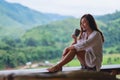 A woman holding and drinking hot coffee on balcony , looking at mountains and green nature