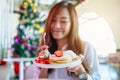 A beautiful asian woman holding and eating pancakes with strawberries and whipped cream Royalty Free Stock Photo