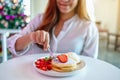 A beautiful asian woman holding and eating pancakes with strawberries and whipped cream Royalty Free Stock Photo