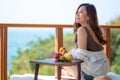 Beautiful asian woman holding fruits while enjoy sitting at balcony with the sea view background Royalty Free Stock Photo
