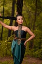 Beautiful Asian woman holding her black hair while standing in front of the forest in a green costume Royalty Free Stock Photo