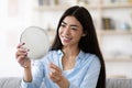 Beautiful Asian Woman Holding Magnifying Mirror At Home, Looking At Her Reflection Royalty Free Stock Photo