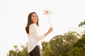 Beautiful Asian woman holding windmill having a good time in sunlight at the park with copy space, concept carefree woman, happy