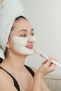 Adorable young Asian woman wears a white clay mask on her face at home. Facial skin care, beauty and youth Royalty Free Stock Photo
