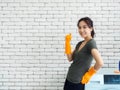 Beautiful Asian woman, housewife wearing orange protective rubber gloves in laundry room Royalty Free Stock Photo