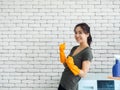 Beautiful Asian woman, housewife wearing orange protective rubber gloves in laundry room Royalty Free Stock Photo