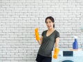 Beautiful Asian woman, housewife wearing orange protective rubber gloves in laundry room Royalty Free Stock Photo