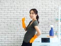 Beautiful Asian woman, housewife wearing orange protective rubber gloves in laundry room Royalty Free Stock Photo