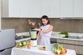 Beautiful Asian Woman juicing making green juice with juice machine in home kitchen. Healthy concept