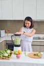 Beautiful Asian Woman juicing making green juice with juice machine in home kitchen. Healthy concept