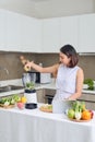 Beautiful Asian Woman juicing making green juice with juice machine in home kitchen. Healthy concept
