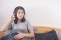 Beautiful Asian woman listening music with headphone relaxing on the bed..