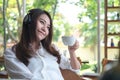 A beautiful Asian woman listening to music with headphone while drinking coffee with feeling happy and relax in cafe Royalty Free Stock Photo