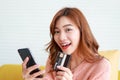 Beautiful asian woman live in an apartment holding a black smartphone and credit card to order online. Royalty Free Stock Photo