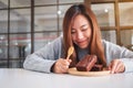 A beautiful asian woman looking and eating delicious brownie cake in wooden plate Royalty Free Stock Photo